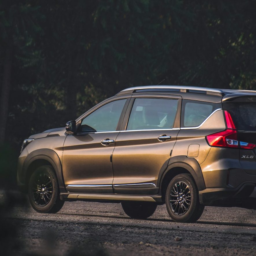 Silver SUV parked on a gravel road surrounded by greenery.