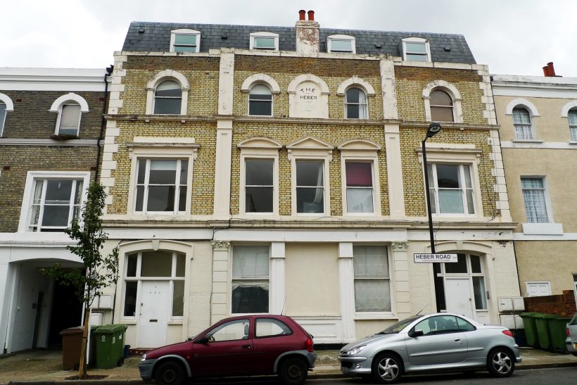 Three-storey townhouse with a decorative façade, parked cars in front.