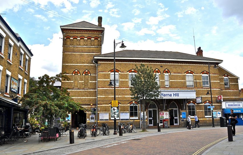 Victorian-style building with brick facade and tower, featuring shops and vibrant street life.