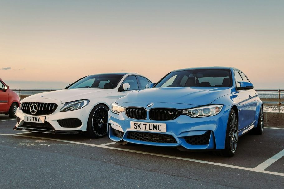 Two sports cars parked side by side: a white Mercedes and a blue BMW.