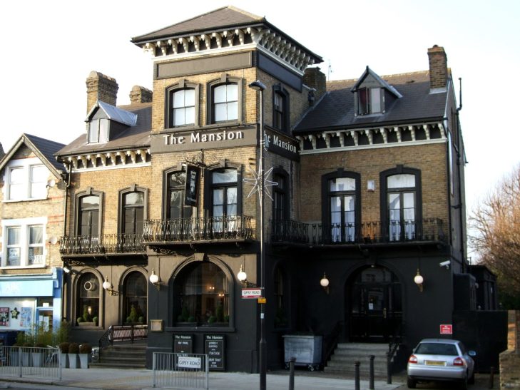 A large, Victorian-style building with a dark facade and balconies, housing a pub.
